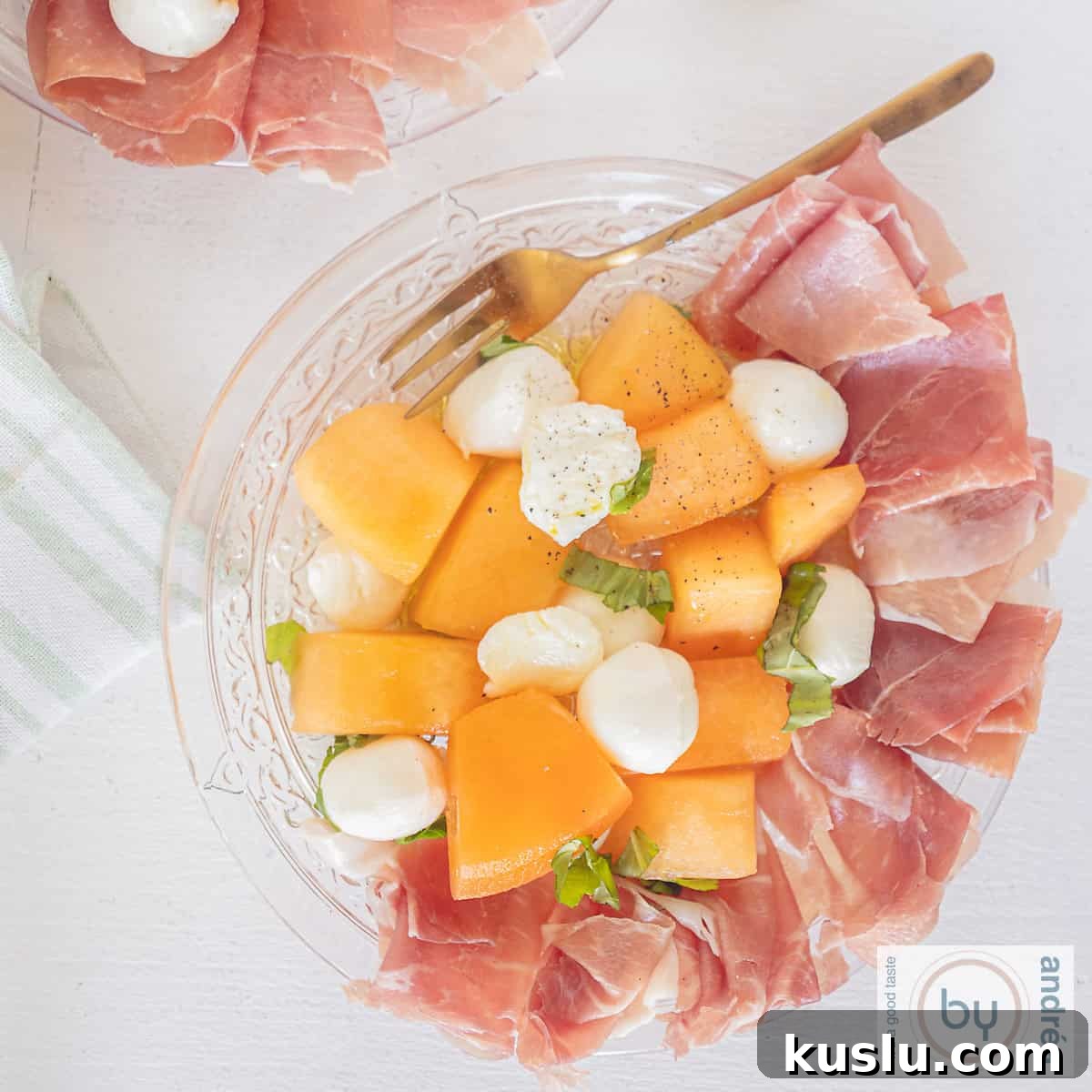 A square picture a glass plate with Parma ham, melon, mozzarella and basil.