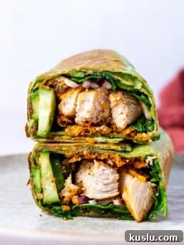 two halves of a chicken hummus wrap stacked on a plate