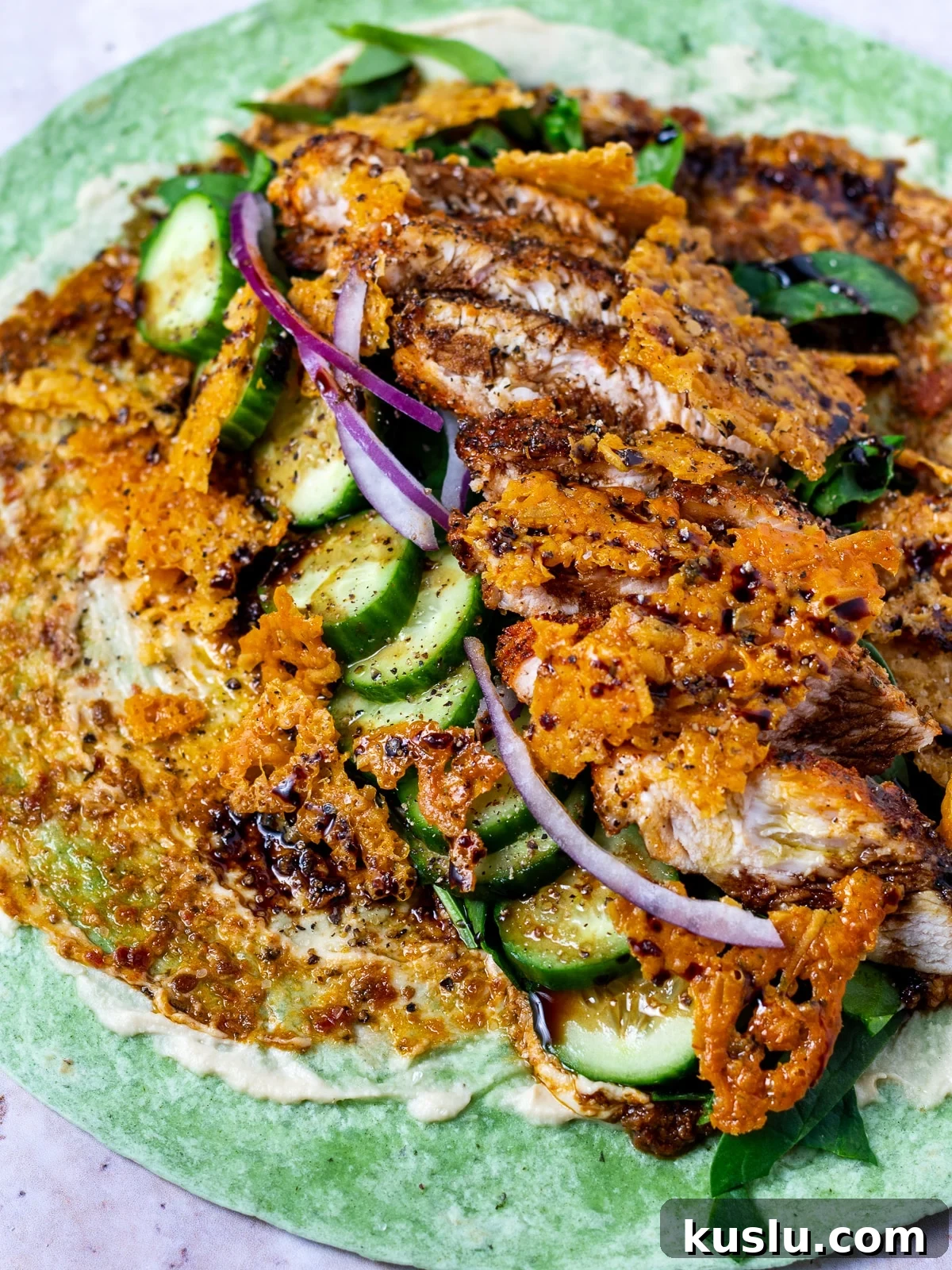 garden spinach herb tortilla spread with hummus, sun-dried tomato pesto, spinach, cucumbers, red onion, seasoned chicken and crispy parmesan