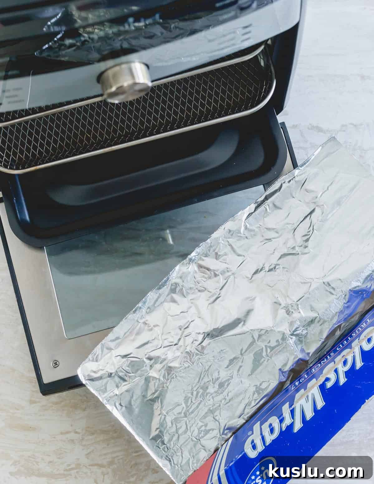 Pampered Chef deluxe air fryer with aluminum foil next to it. Pampered Chef deluxe air fryer with aluminum foil next to it.