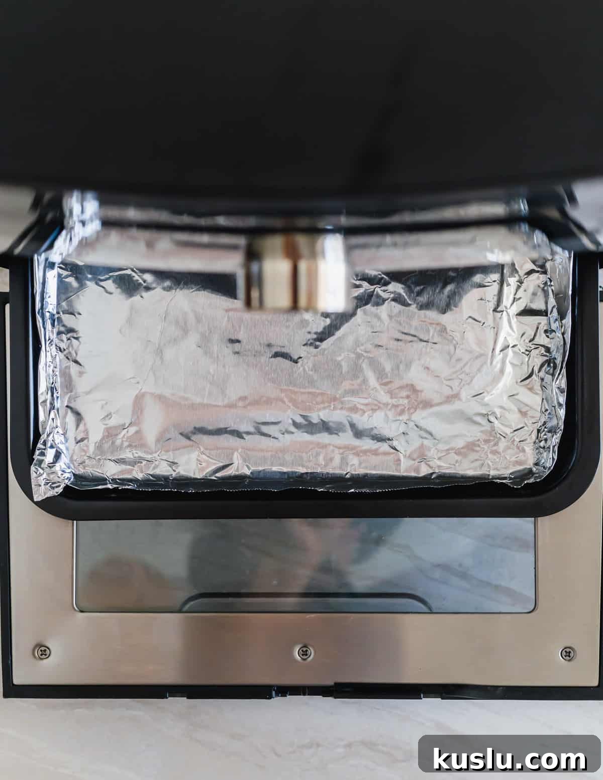 Bottom tray of an air fryer oven lined with tin foil. Bottom tray of an air fryer oven lined with tin foil.