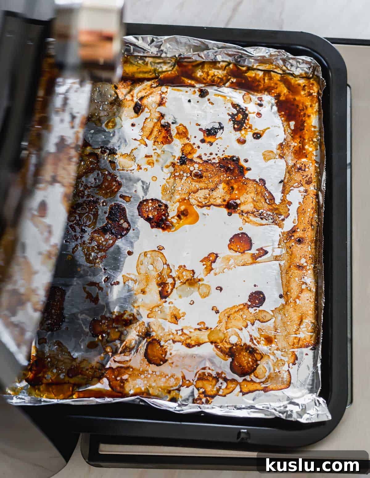 Tin foil lined grease tray in an air fryer oven after cooking. Tin foil lined grease tray in an air fryer oven after cooking.