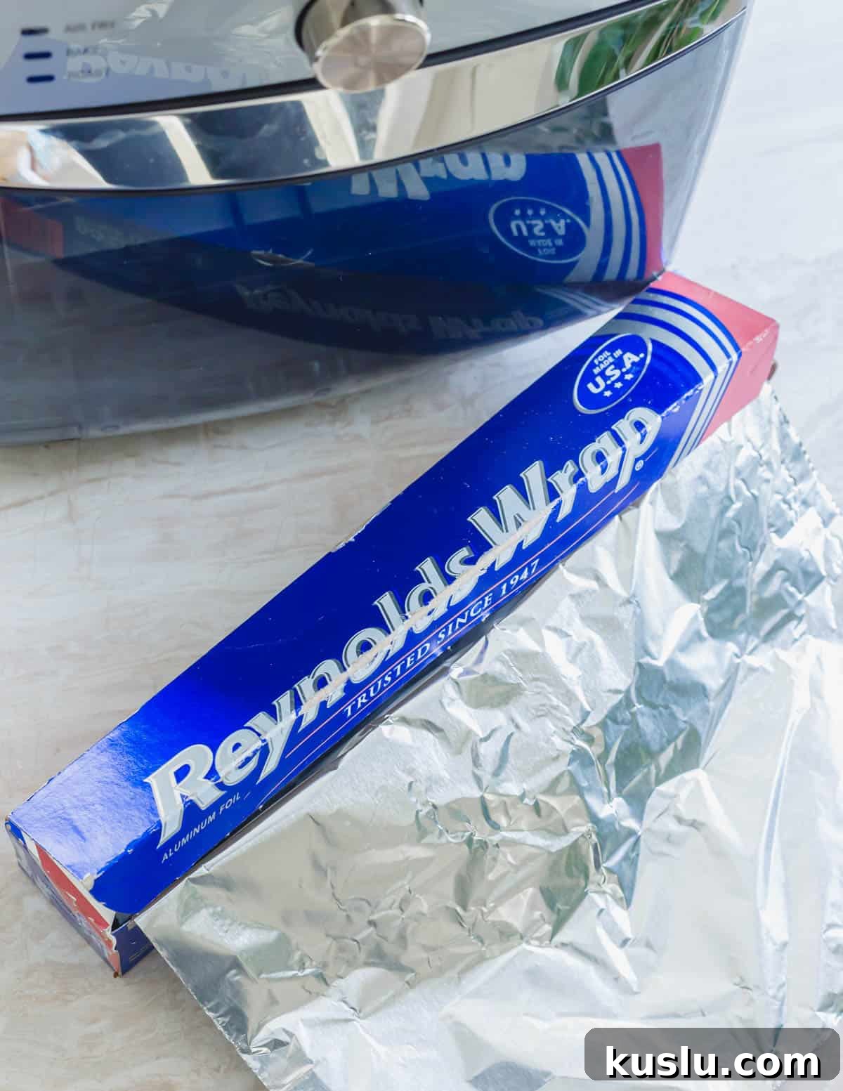 Reynold's Wrap aluminum foil next to an air fryer. Reynold's Wrap aluminum foil next to an air fryer.