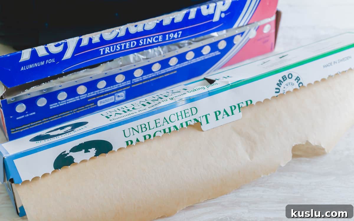 Unbleached parchment paper and aluminum foil next to an air fryer. Unbleached parchment paper and aluminum foil next to an air fryer.