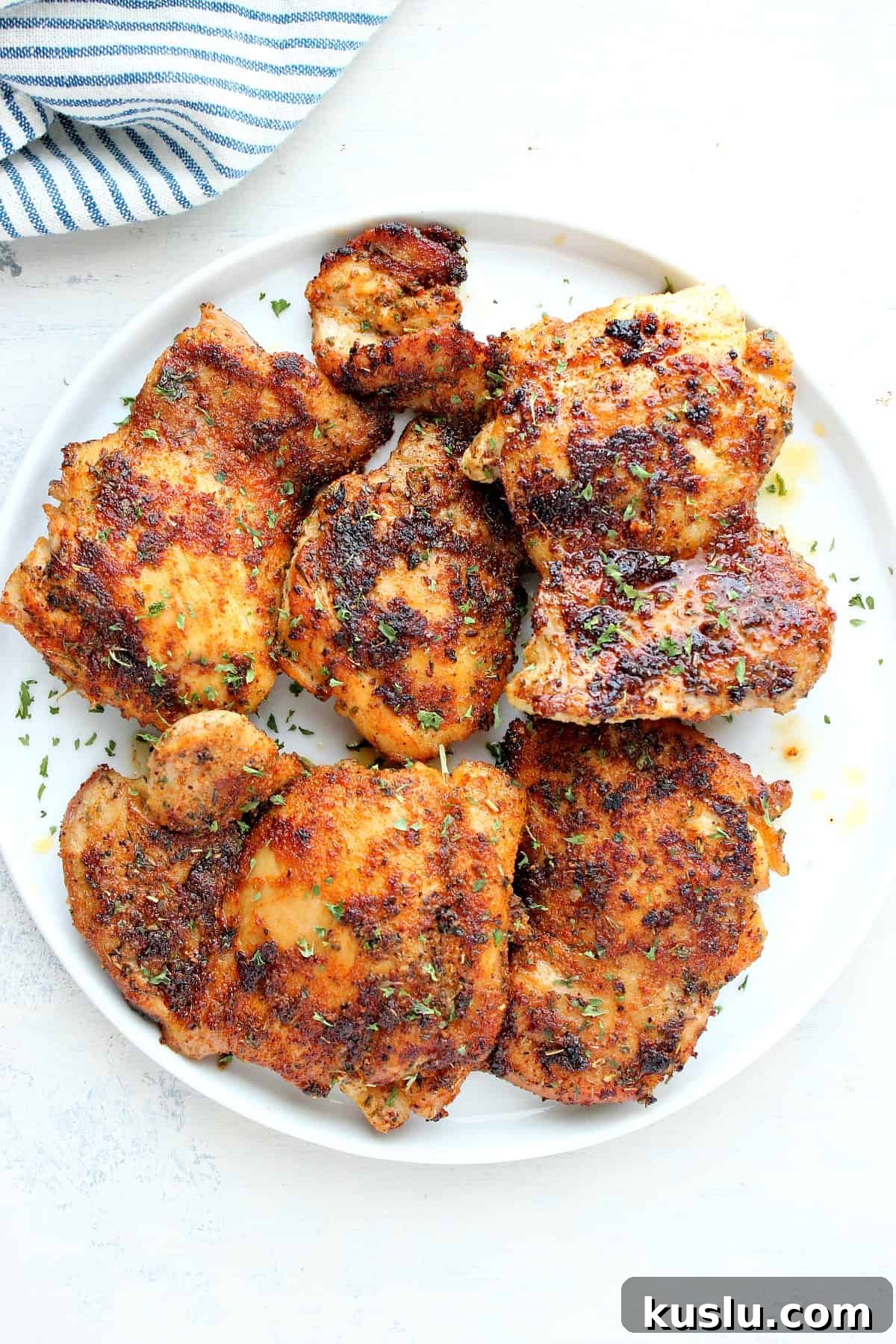 Skillet Chicken Thighs Recipe Cooked chicken thighs on a white plate.