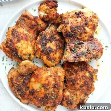 Cooked chicken thighs on a white plate.