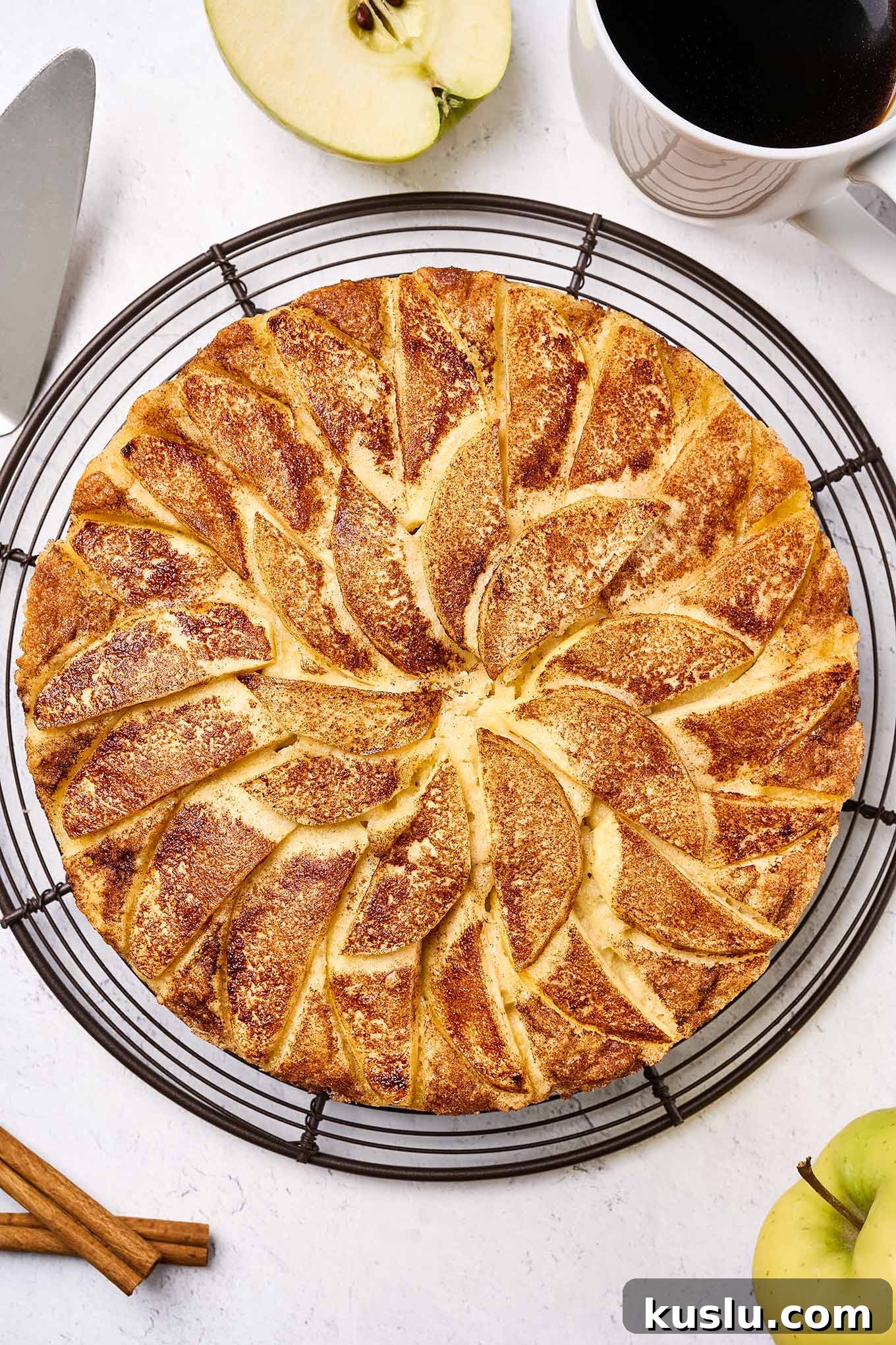 Moist Golden Delicious Apple Cake Recipe for Fall Baking 9 Freshly baked apple cake topped with sliced Golden Delicious apples and cinnamon sugar, cooling on a wire rack, waiting to be sliced.