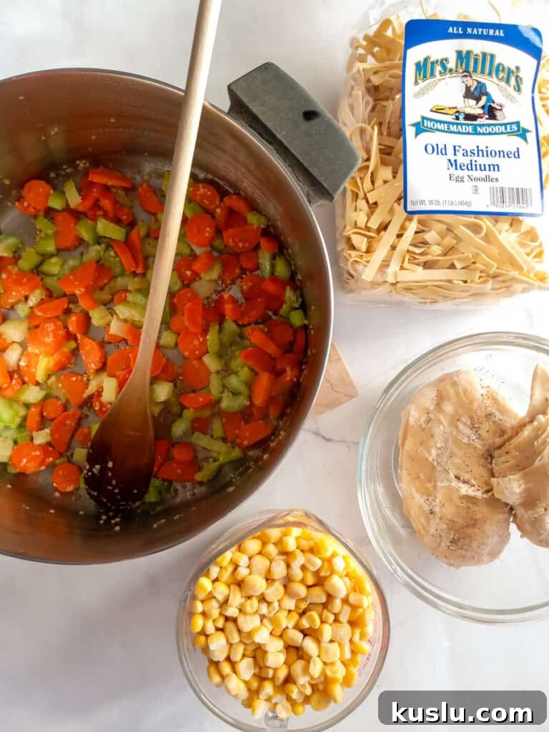 Amish Chicken and Corn Noodle Soup Recipe 3 chopped carrots, celery, and garlic in a large pot, noodles, corn, and chicken in separate dishes.
