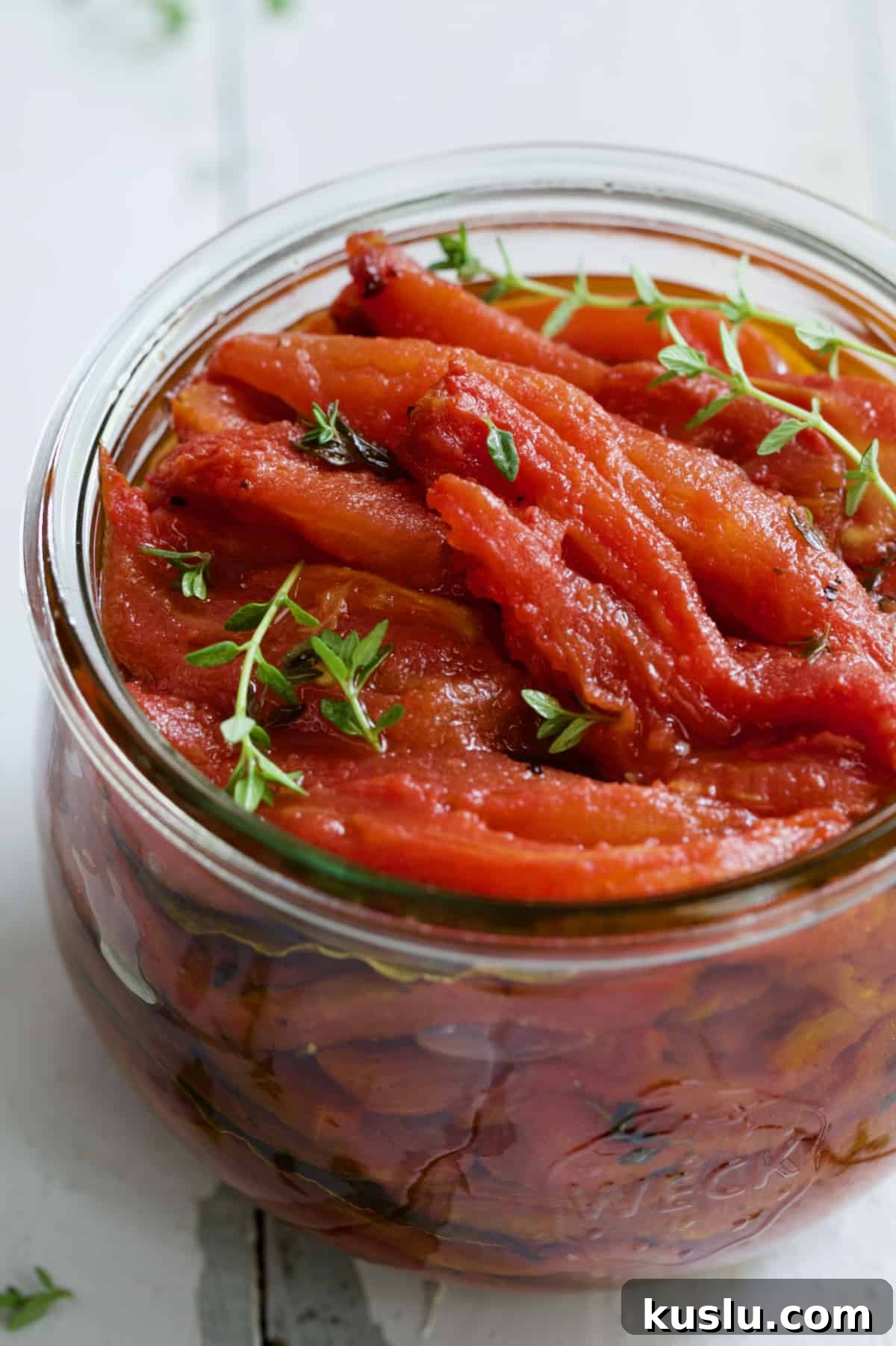 Tomato Confit in glass jar with thyme sprigs.
