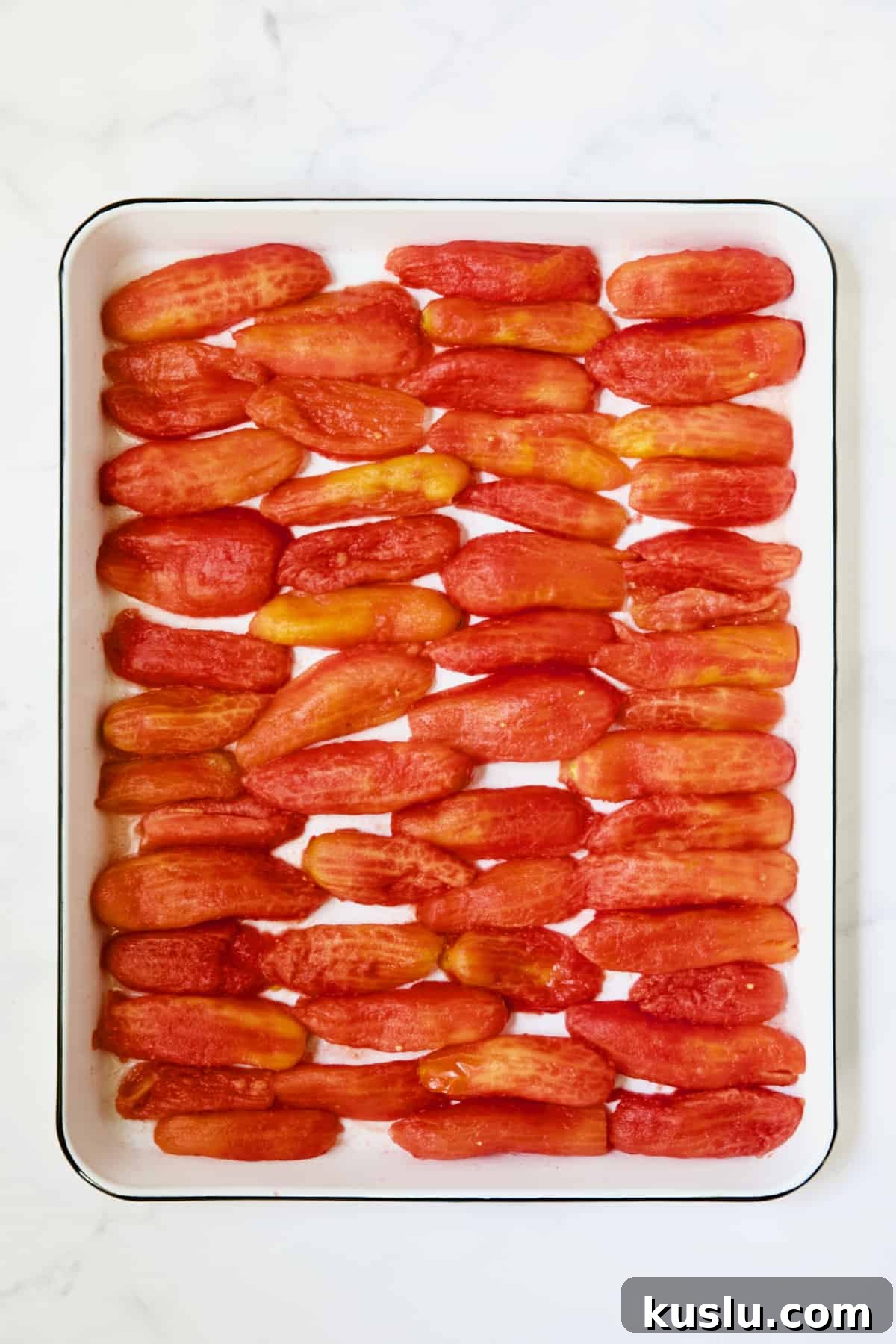 40 plum tomato halves on white enameled baking sheet.