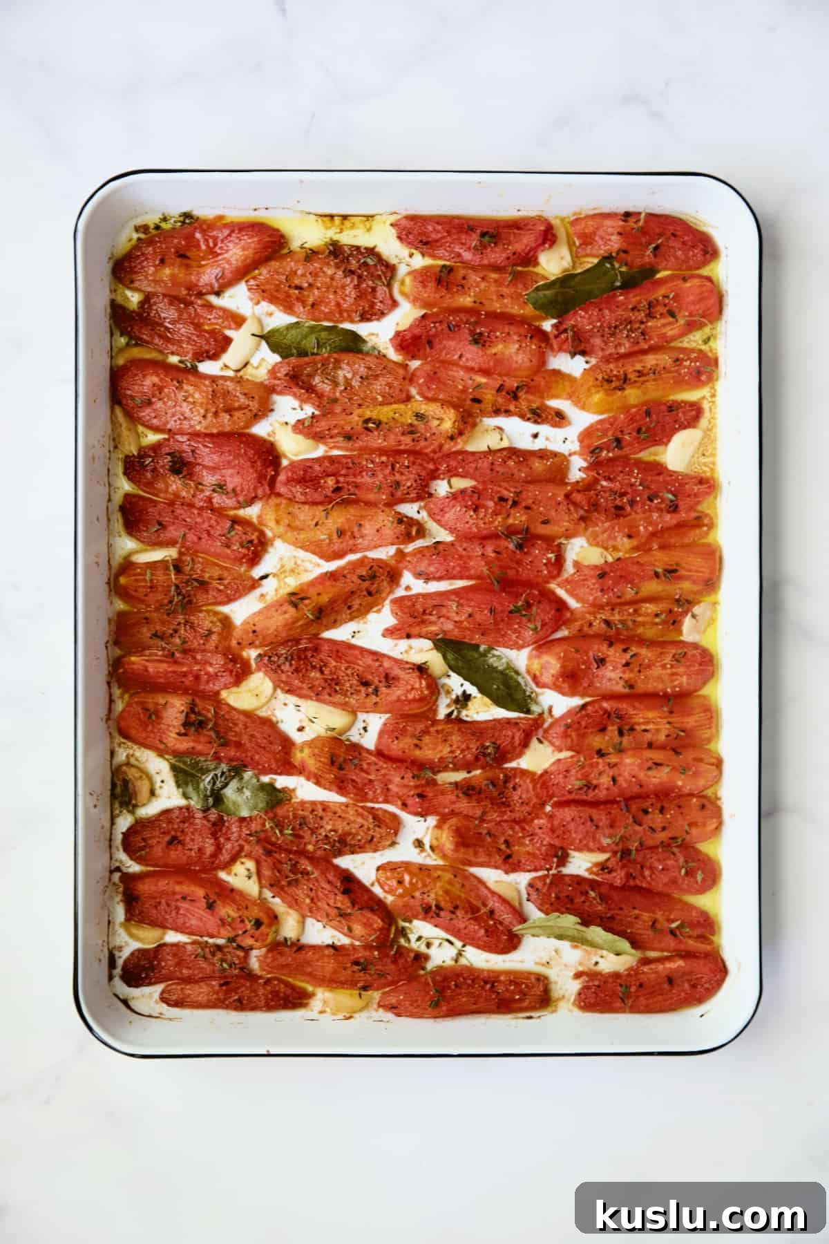 Confit tomatoes on white enameled baking sheet.