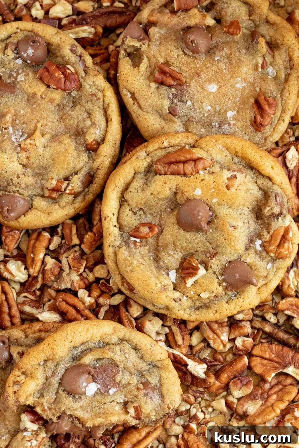 pecan chocolate chip cookies laying on top of chopped pecans