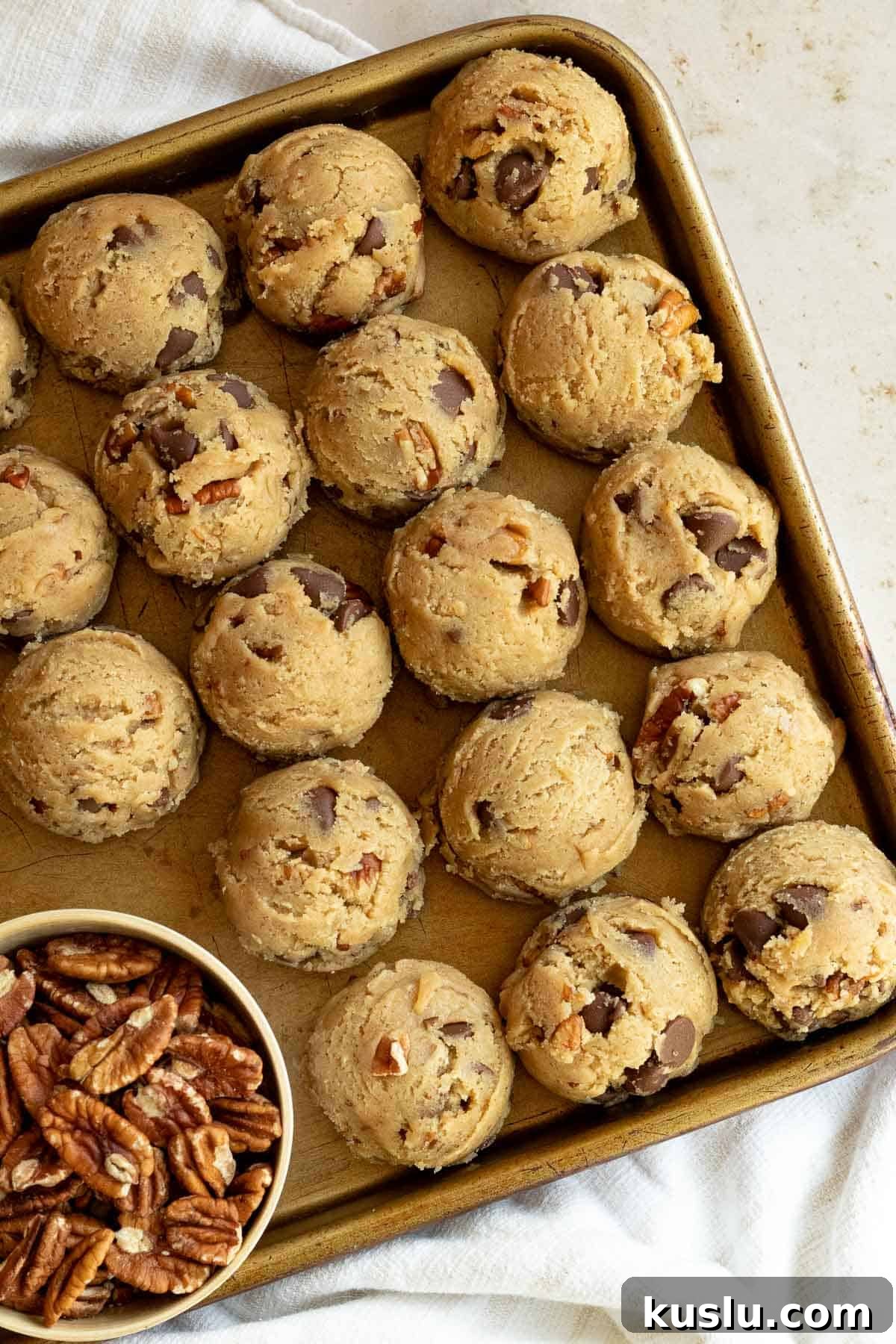 balls of pecan chocolate chip cookie dough on a cookie sheet