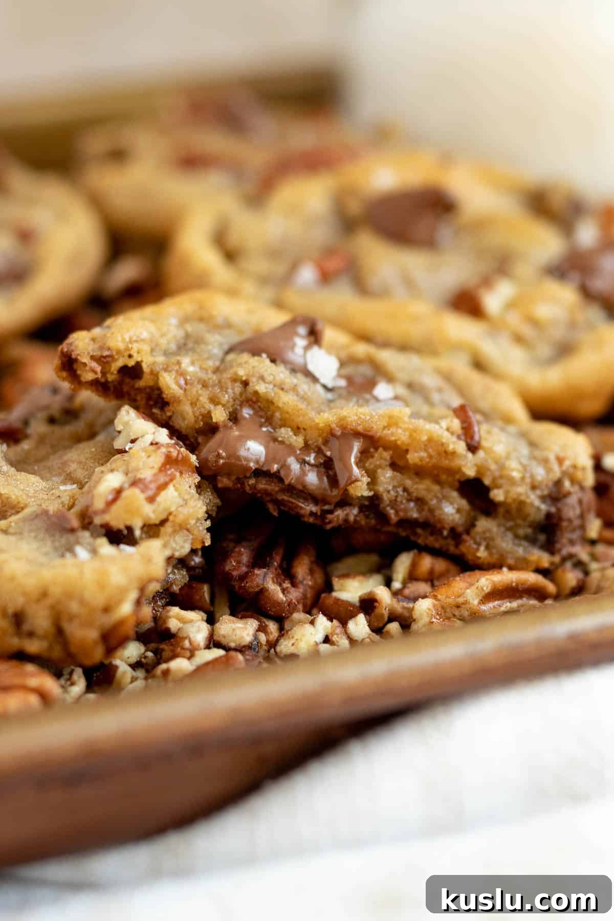 pecan chocolate chip cookie split in half showing melted chocolate chips