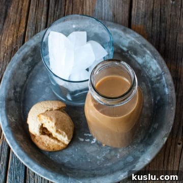 Starbucks Frappuccino copycat in a glass bottle next to a cup of ice and cookies