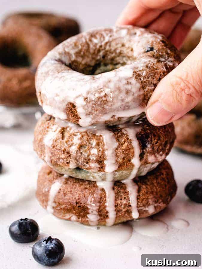 stack of three blueberry glazed cake donuts reaching for top one