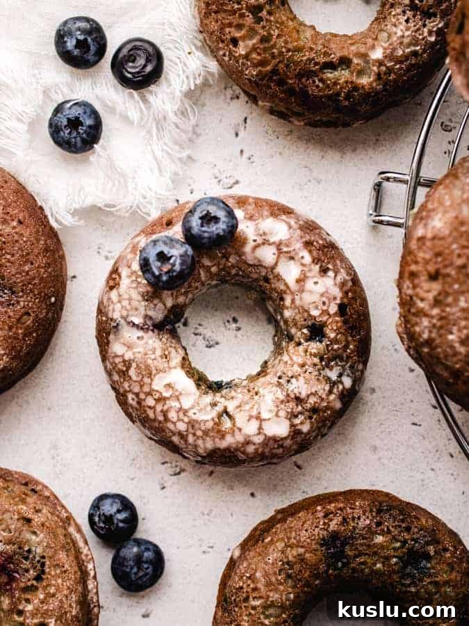 overhead of blueberry cake donut covered in glaze with 2 blueberries on it