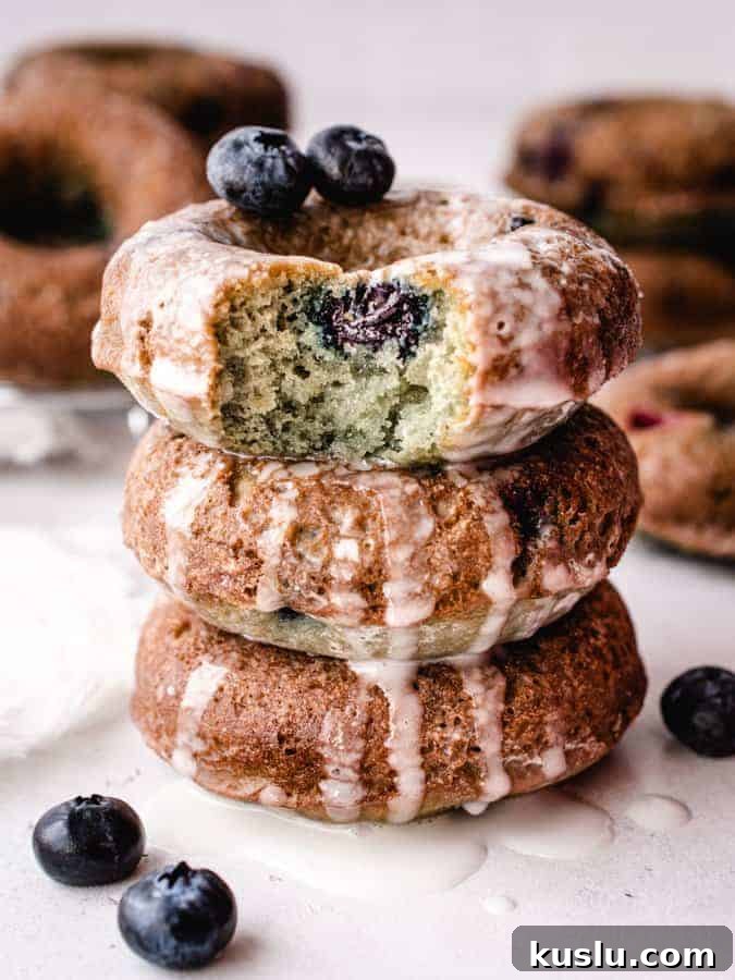 stack of 3 blueberry cake donuts, top donut with bite taken out