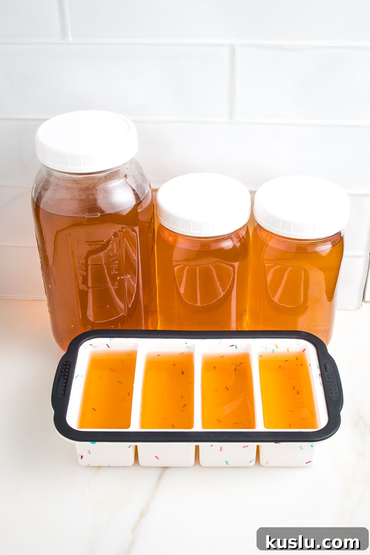 How to Make Flavorful Homemade Vegetable Broth from Scratch 2 Different sized glass mason jars plus silicone ice cube trays filled with golden colored stock, ready for the freezer.