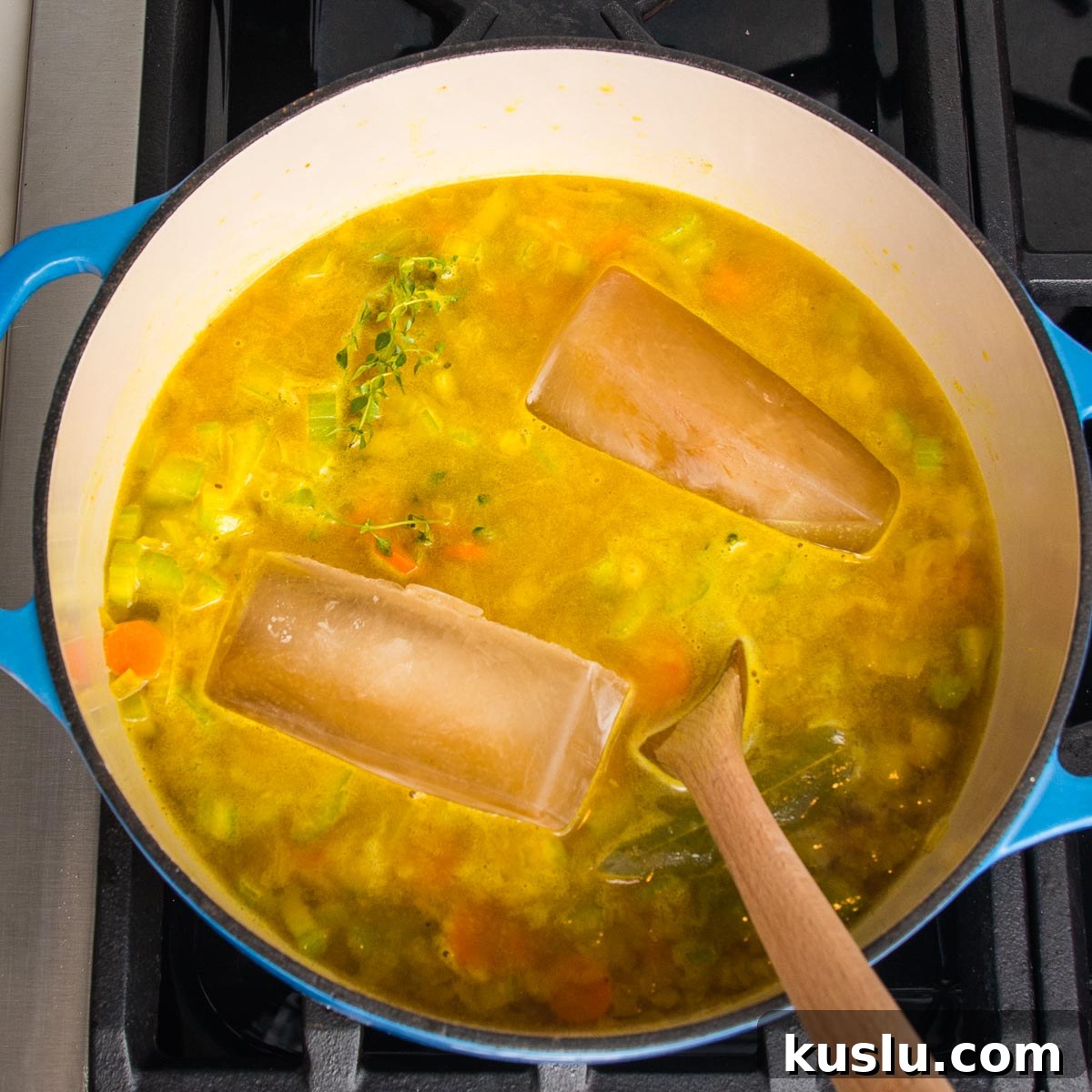 How to Make Flavorful Homemade Vegetable Broth from Scratch 7 Dutch oven with soup cooking and a couple large cubes of veggie broth melting into the pot of soup.