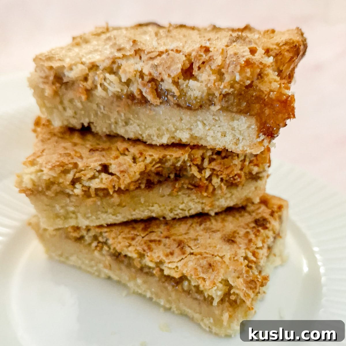 Three slices of coconut jam tart piled one on top of the other.