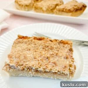 A slice of coconut jam tart on a white plate.
