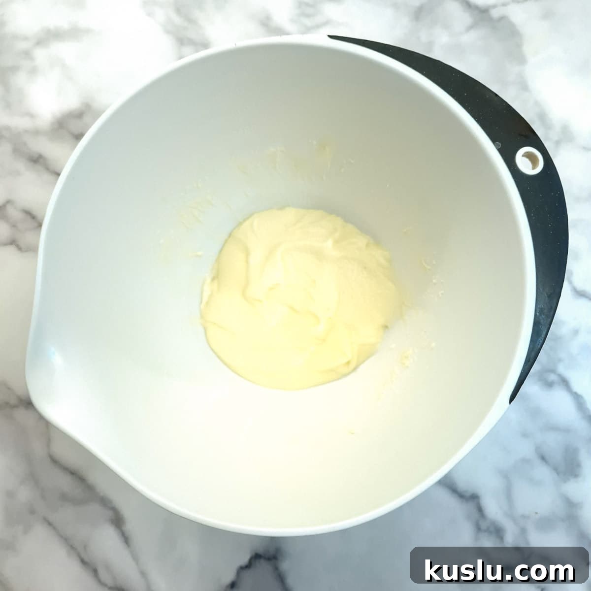 Butter and sugar creamed together in a white mixing bowl.