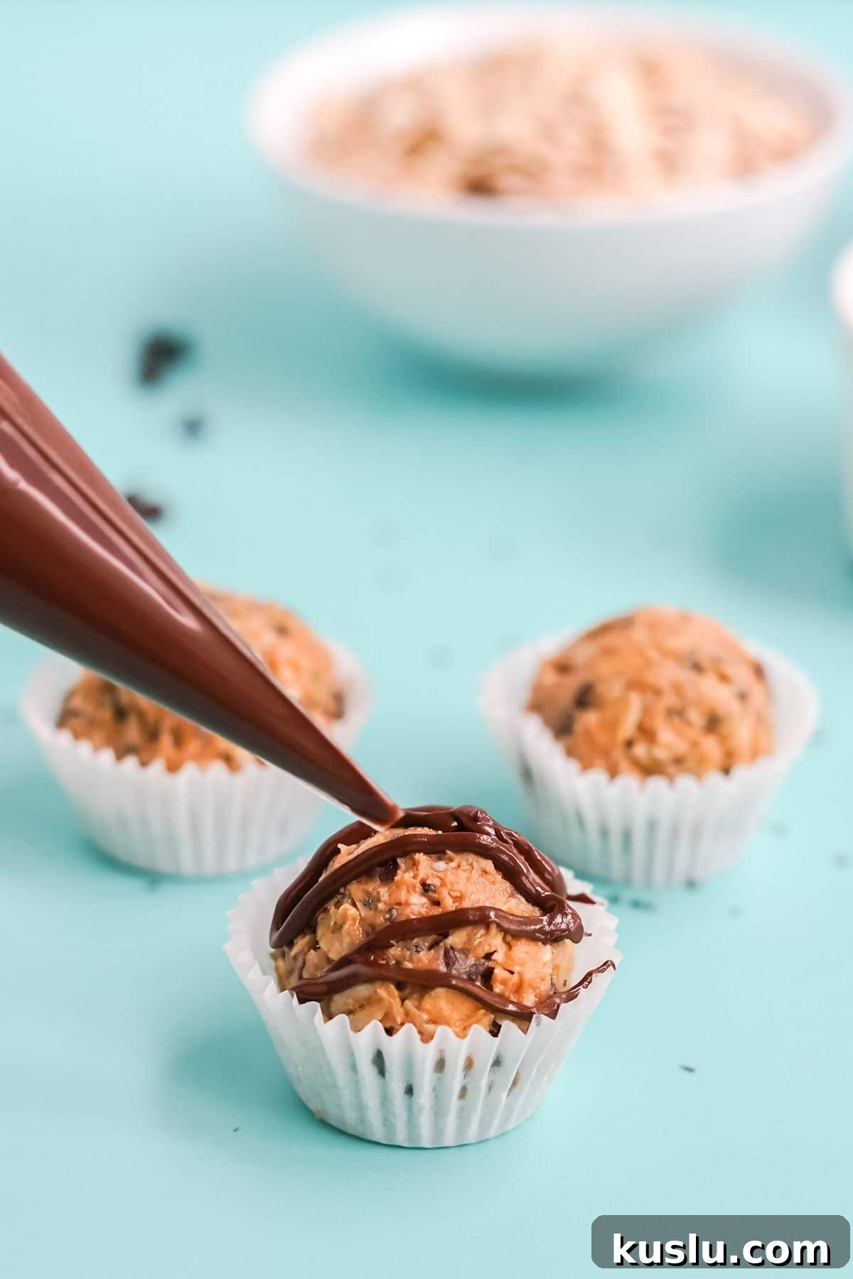 Adding chocolate to the top of protein balls.