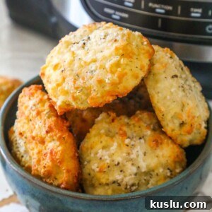 a bowl of rolls stacked in a blue bowl in front of an air fryer machine
