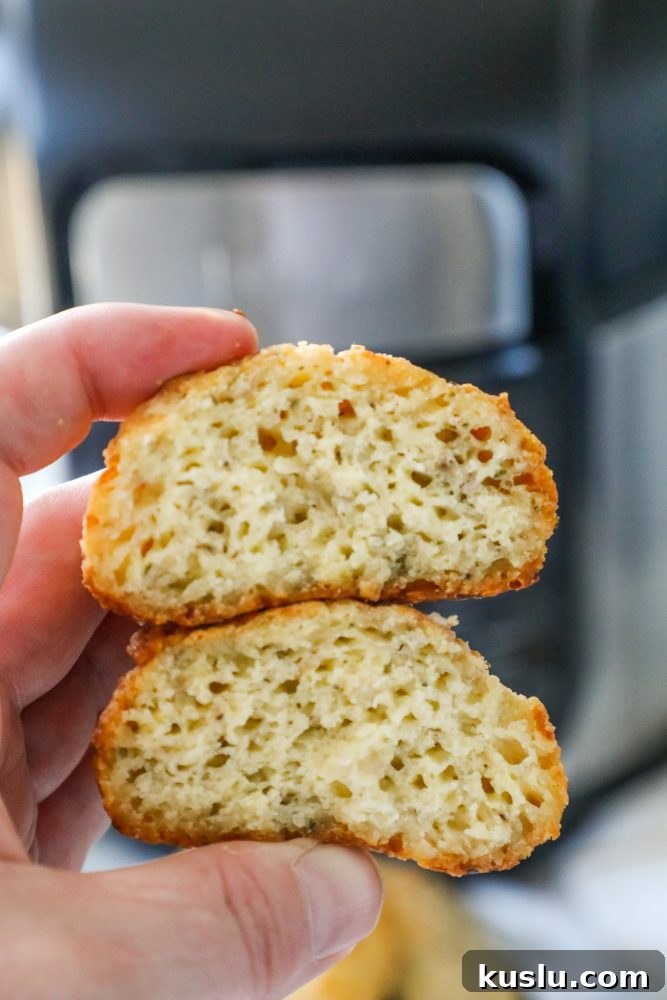 A person holding a piece of bread in front of an air fryer while making keto rolls.