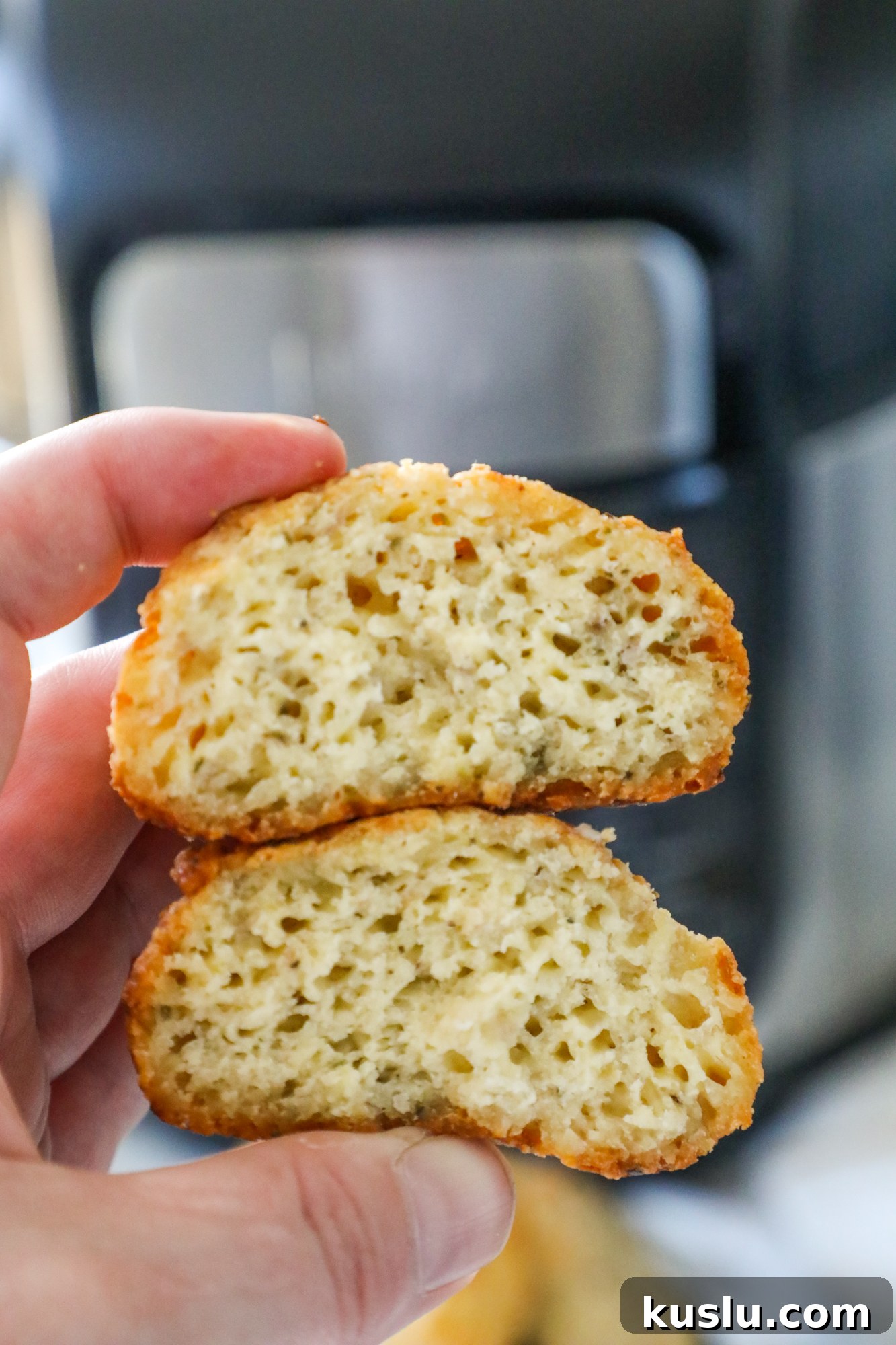 A person holding a piece of bread in front of an air fryer while making keto rolls.