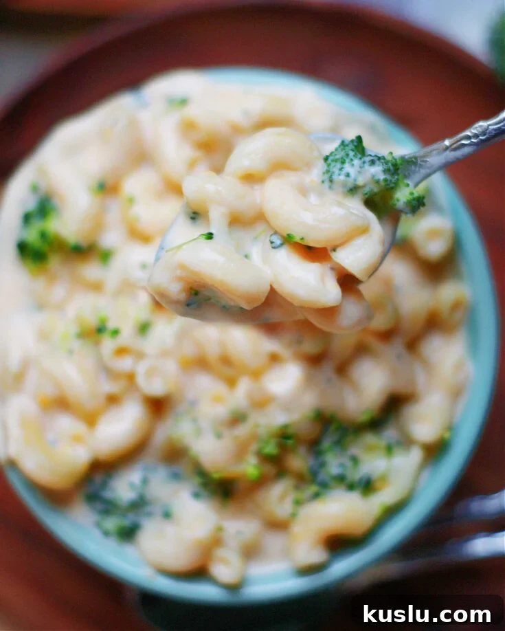 creamy broccoli macaroni and cheese in a bowl with spoon to show cheese sauce, pasta and broccoli