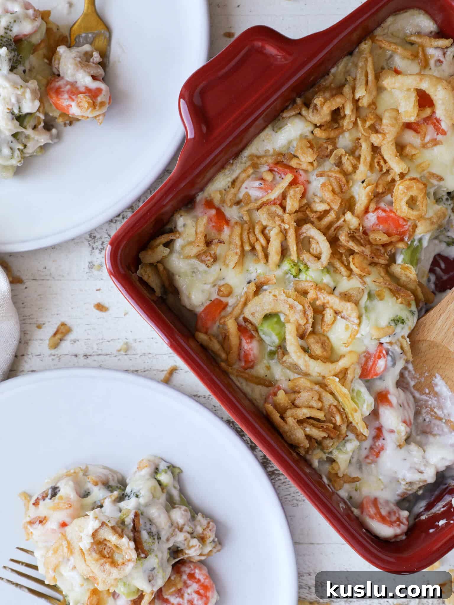 Vegetable casserole served in a red baking dish with two white plates.