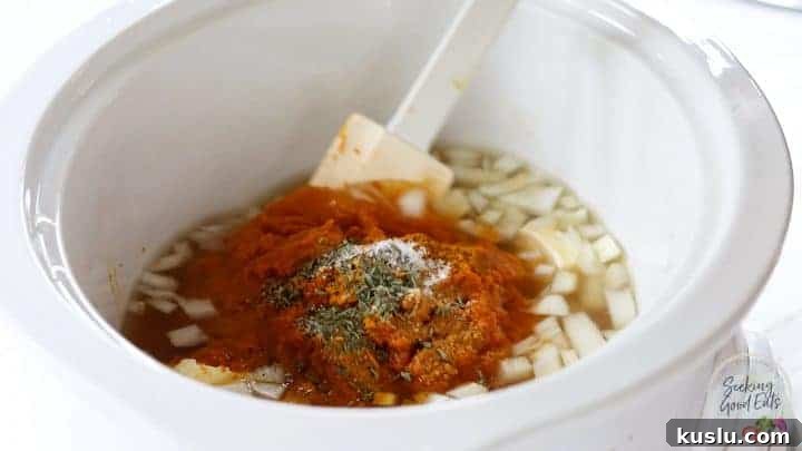 Adding all pumpkin soup ingredients to a large white oval crockpot.