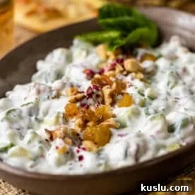 Persian Yogurt and Cucumber Dip (Mast o Khiar) in bowl topped with golden raisins and walnuts