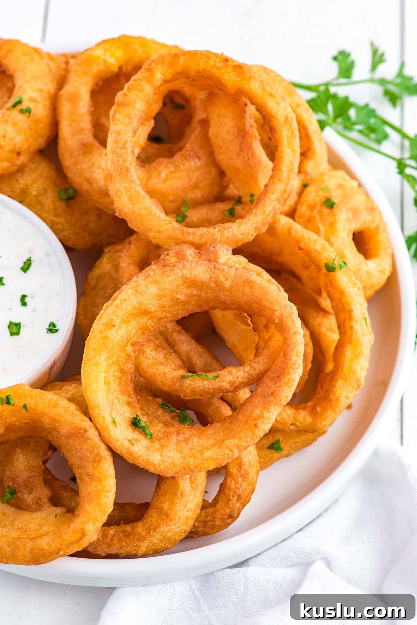 Crispy Frozen Onion Rings in the Air Fryer: Quick Recipe Guide 2 A pile of cooked air fryer onion rings on the table with a bowl of ranch.