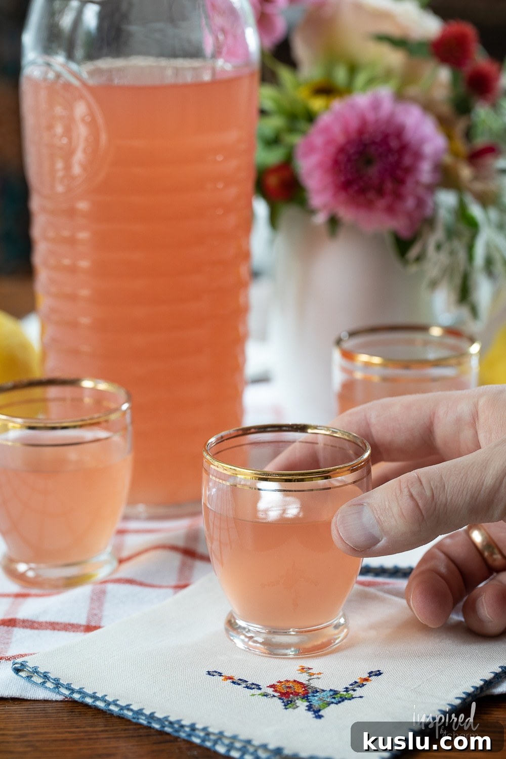 Homemade Rhubarb and Ginger Infused Vodka Recipe 11 hand holding a shot glass of homemade rhubarb ginger vodka.