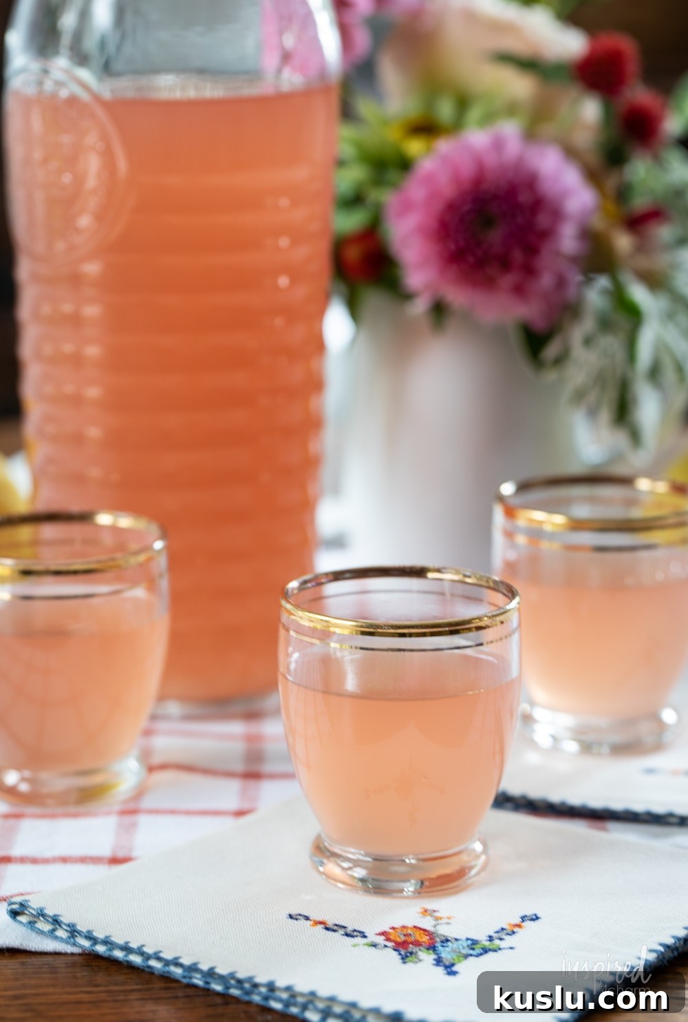 Homemade Rhubarb and Ginger Infused Vodka Recipe 3 hand holding a shot glass filled with homemade rhubarb ginger vodka.