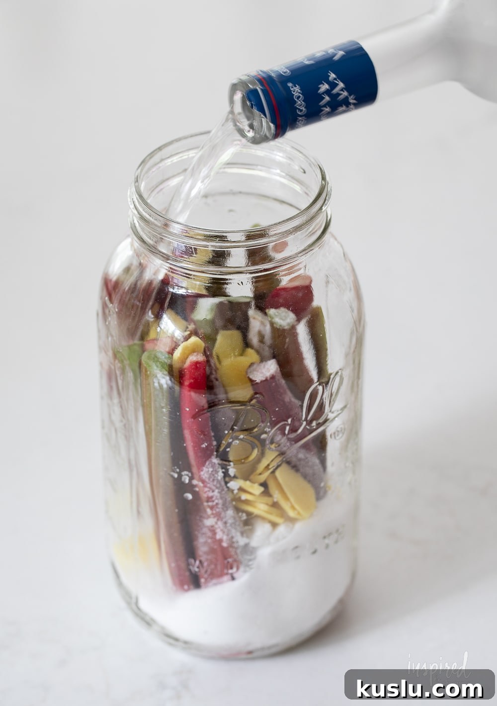Homemade Rhubarb and Ginger Infused Vodka Recipe 6 pouring vodka into a jar with rhubarb and sugar.