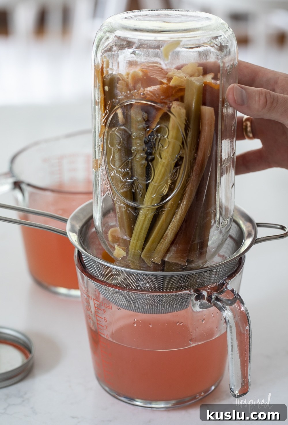 Homemade Rhubarb and Ginger Infused Vodka Recipe 8 straining homemade rhubarb ginger vodka into a jar.