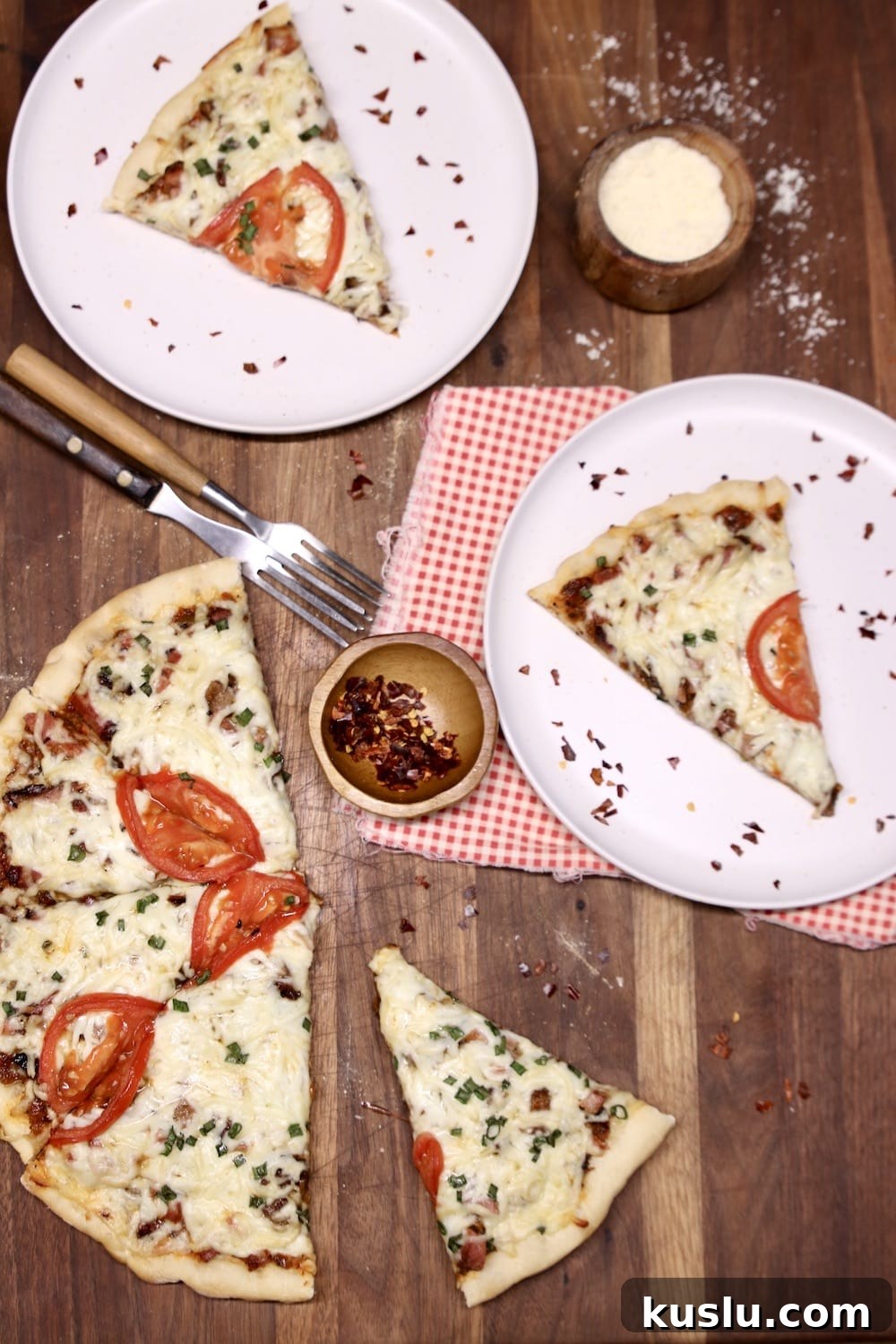 Grilled smoked brisket pizza grilled pizza, sliced, 2 plates with a slice, red peppers, parmesan cheese in a small bowl