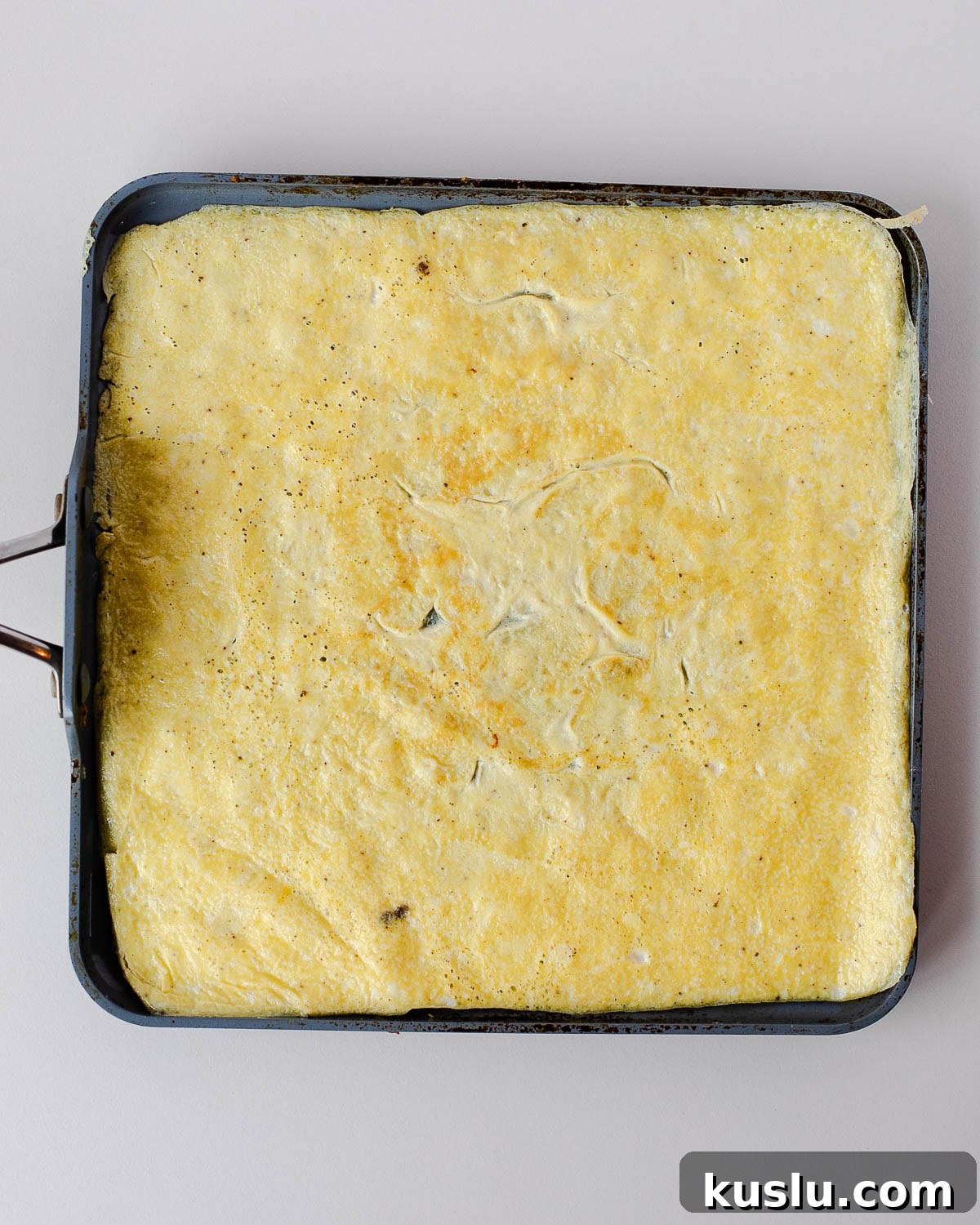 Thin layer of cooked eggs in a baking pan, prepared for cutting into heart shapes.