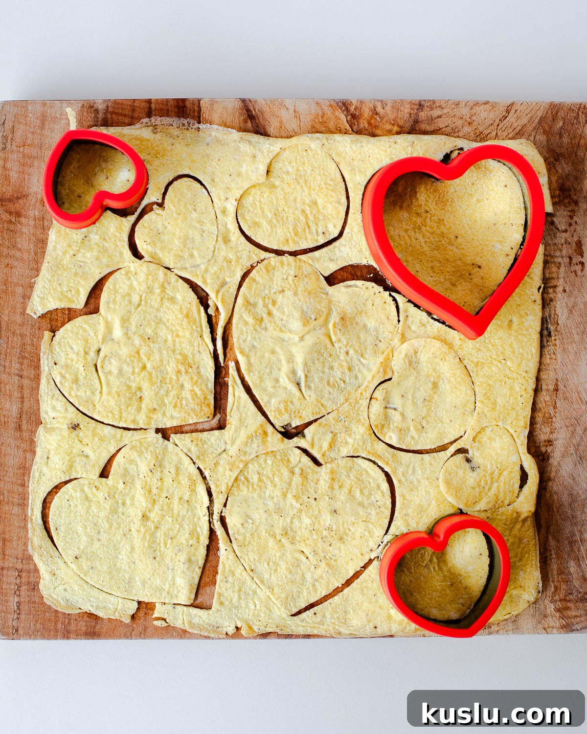 Heart-shaped eggs cut from a sheet of cooked eggs using heart cookie cutters.