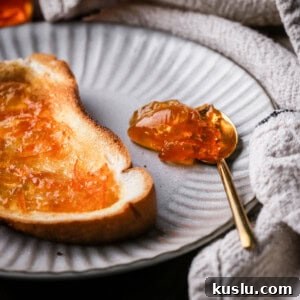 Seville Orange Marmalade on toast next to a teaspoonful of marmalade.