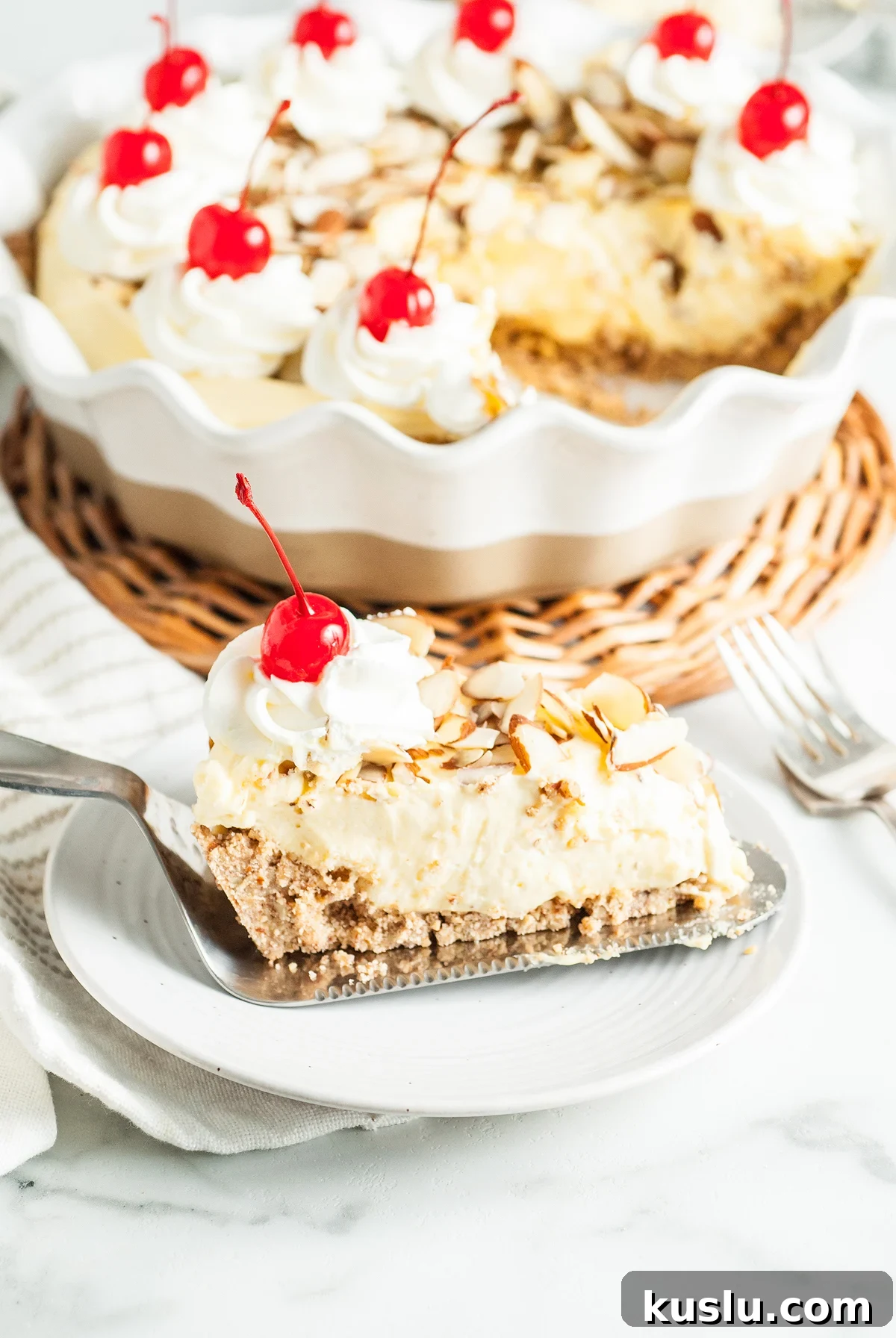 Decadent Amaretto Cream Pie Recipe with Almond Liqueur Filling 3 Slice of Amaretto Cream Pie topped with whipped cream, cherries, and almond slices, served on a white plate—a decadent Italian inspired dessert with a delicate almond crust.