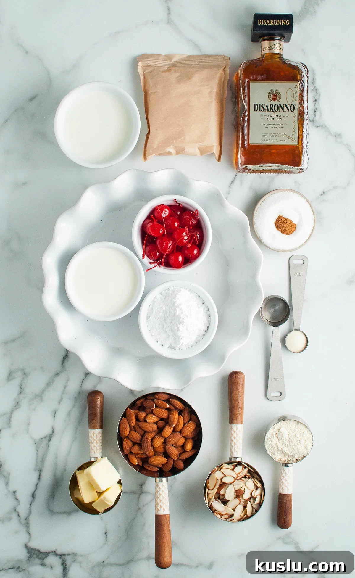 Decadent Amaretto Cream Pie Recipe with Almond Liqueur Filling 5 Ingredients for a dessert with amaretto liqueur, including almonds, butter, cherries, milk, sugar, flour, and spices are arranged on a marble counter—perfect for creating an Amaretto Cream Pie with almond crust.