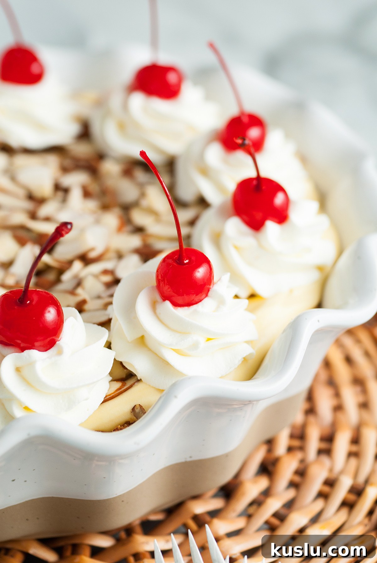 Decadent Amaretto Cream Pie Recipe with Almond Liqueur Filling 6 A pie with an almond crust, topped with whipped cream swirls, maraschino cherries, and sliced almonds in a decorative dish—a truly Italian inspired dessert.