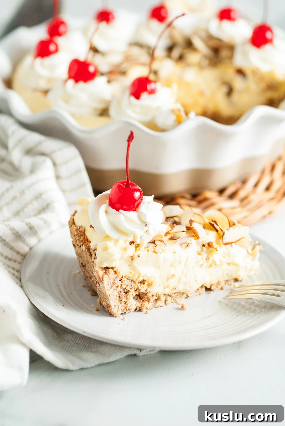 Decadent Amaretto Cream Pie Recipe with Almond Liqueur Filling 8 A slice of creamy Amaretto Cream Pie with whipped cream, almonds, and a cherry on top sits in front of more pie—an irresistible Italian inspired dessert with a delicate almond crust.