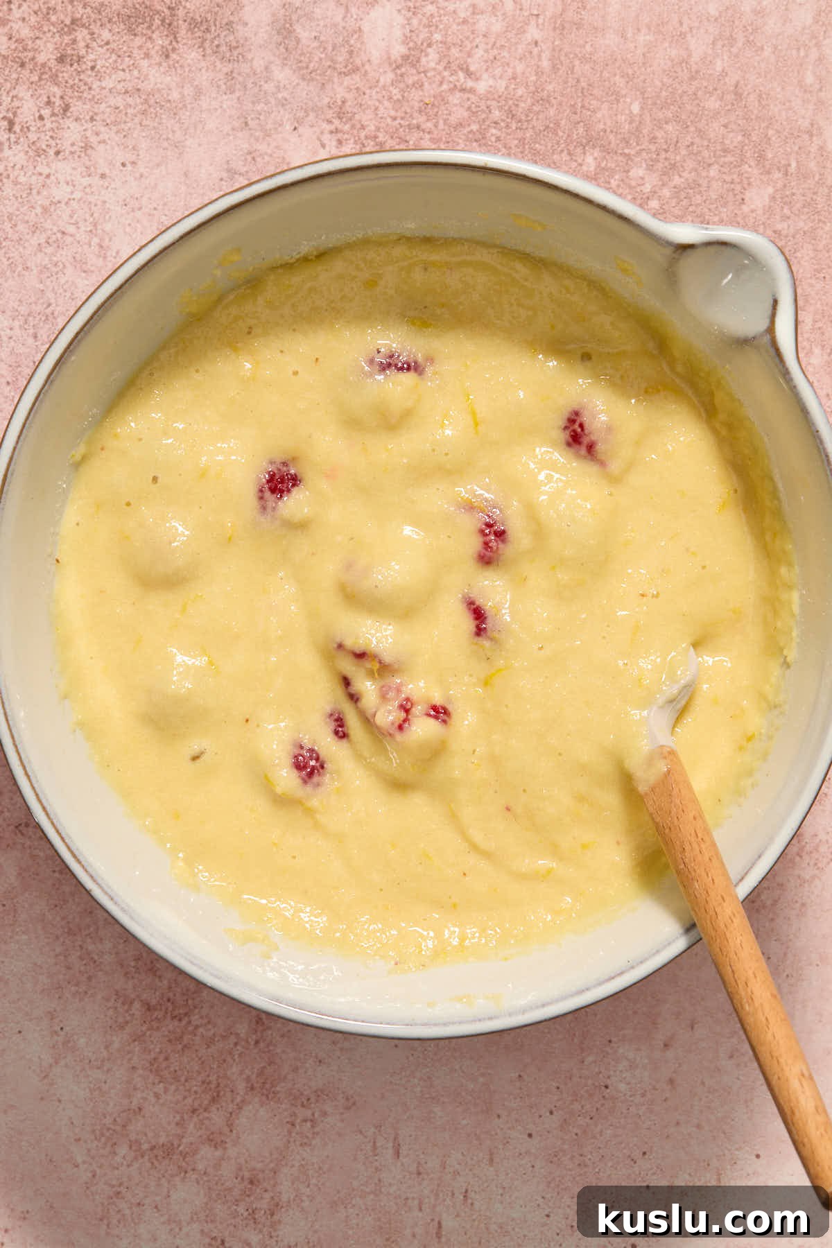 Raspberries folded into the cake batter with a spatula.