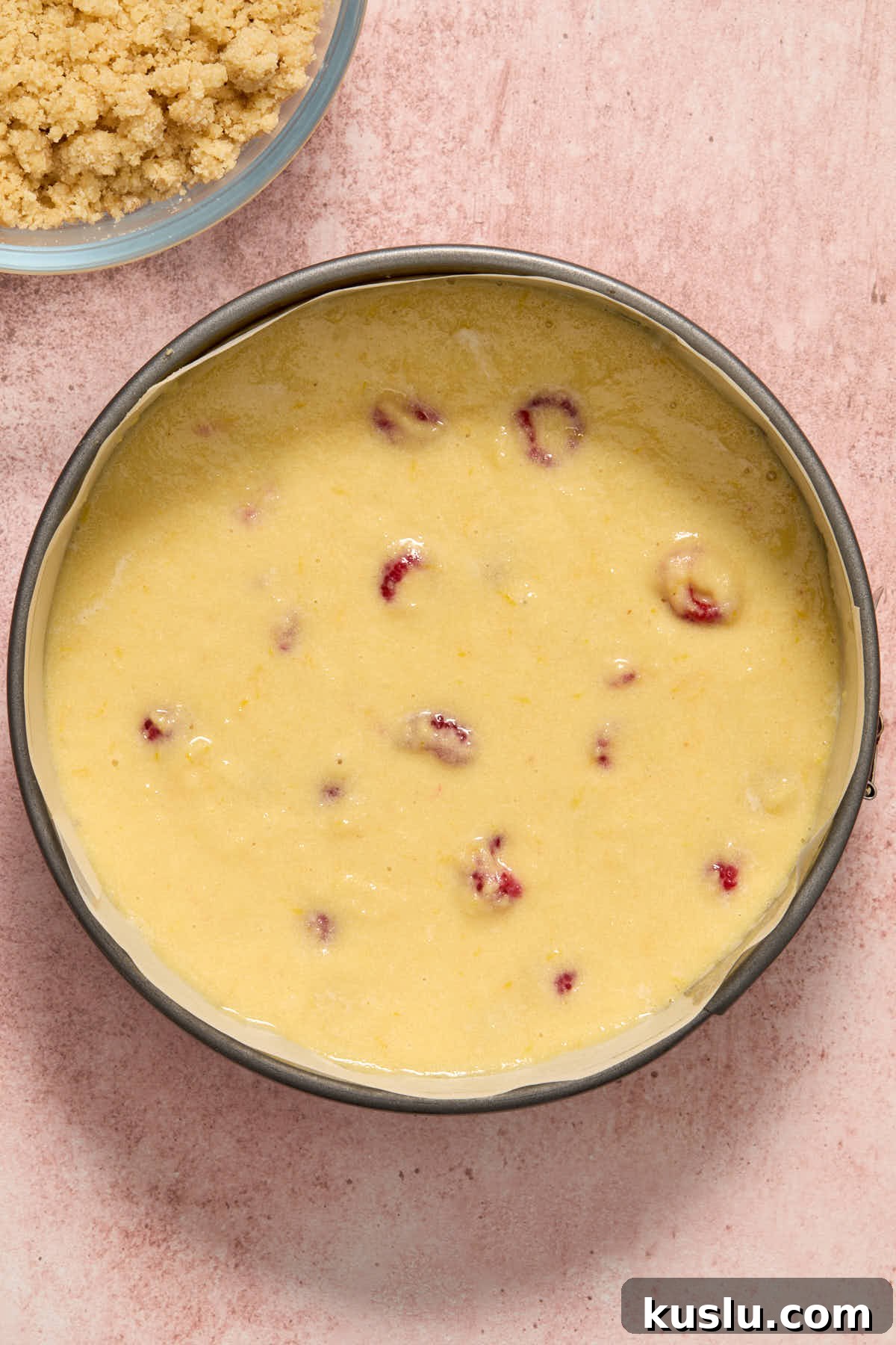 Cake batter spread out in a springform pan lined with parchment paper.